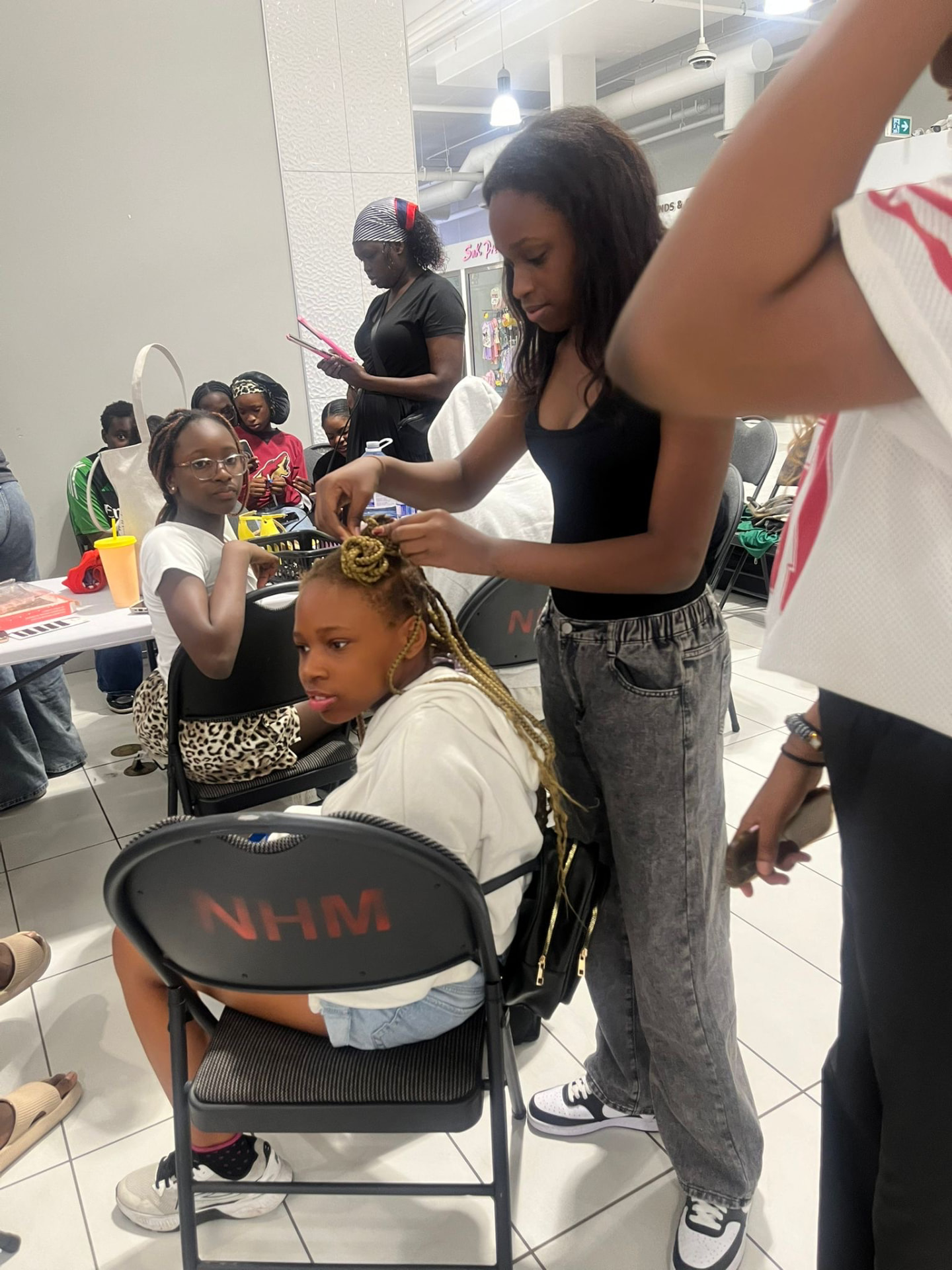 A student adds finishing braids for a young guest at the graduation celebration