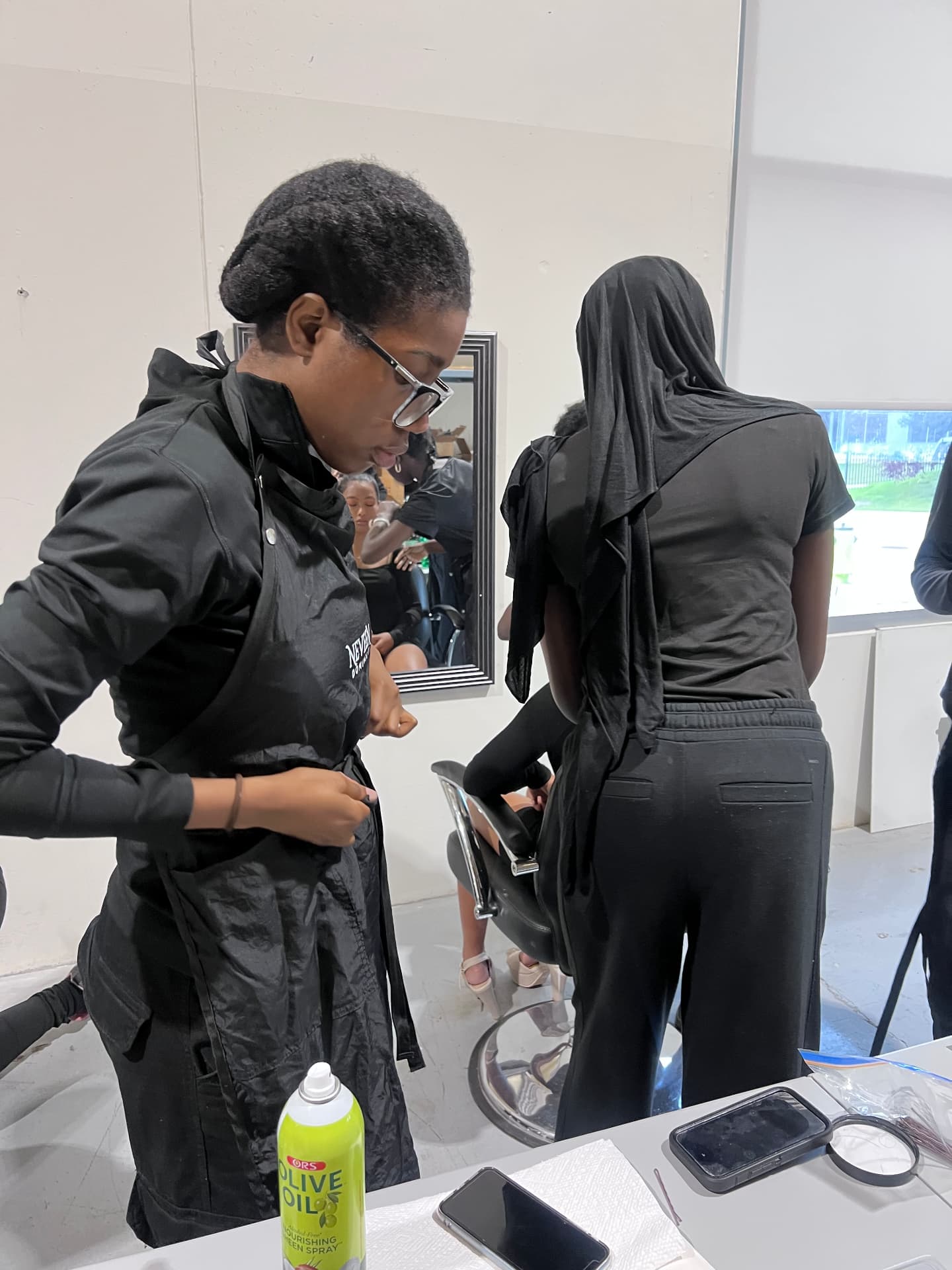 A camper ties her NEVEEN DOMINIC apron backstage before the fashion show