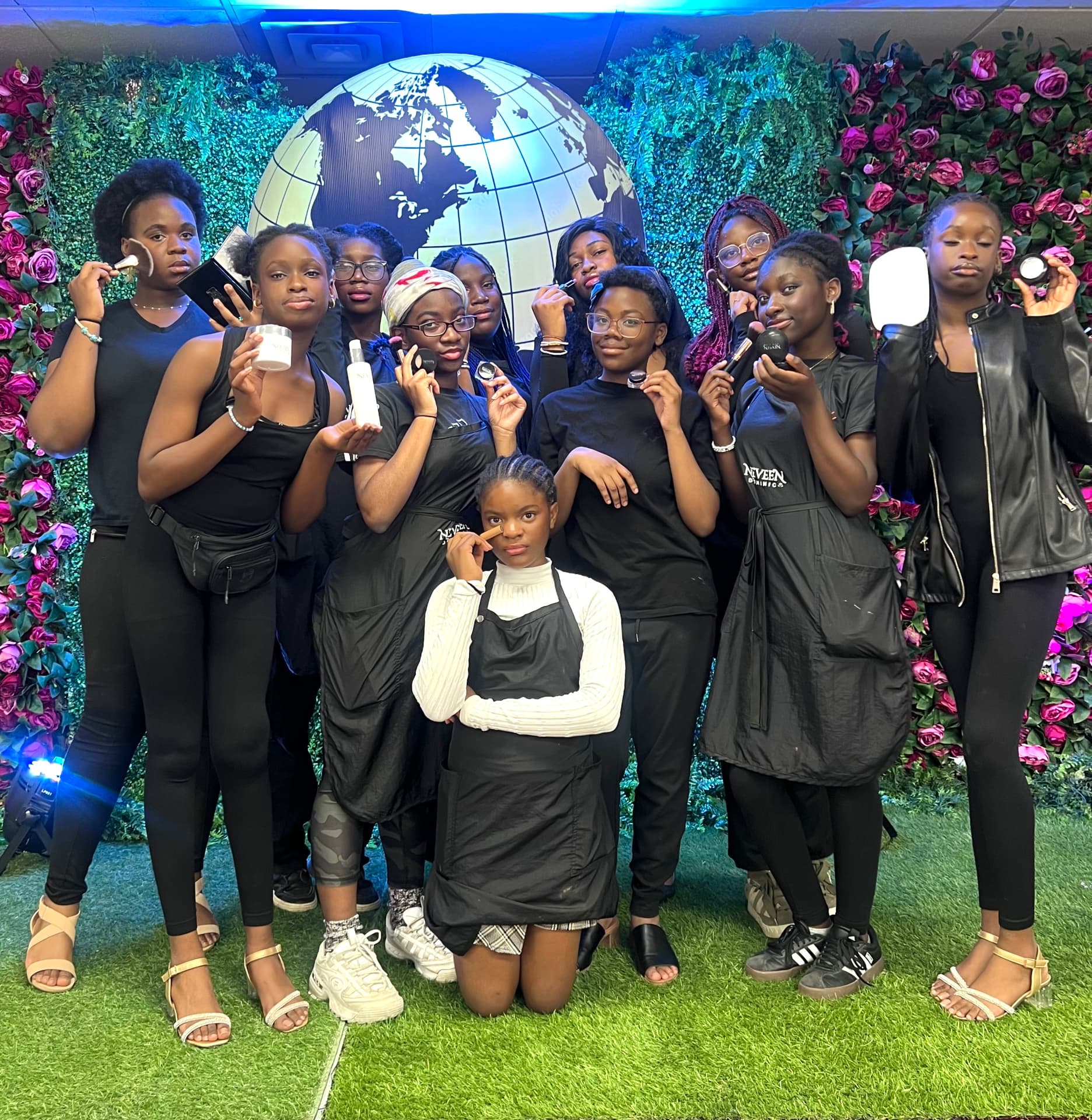 The backstage team poses with Neveen Dominic products in front of a flower wall