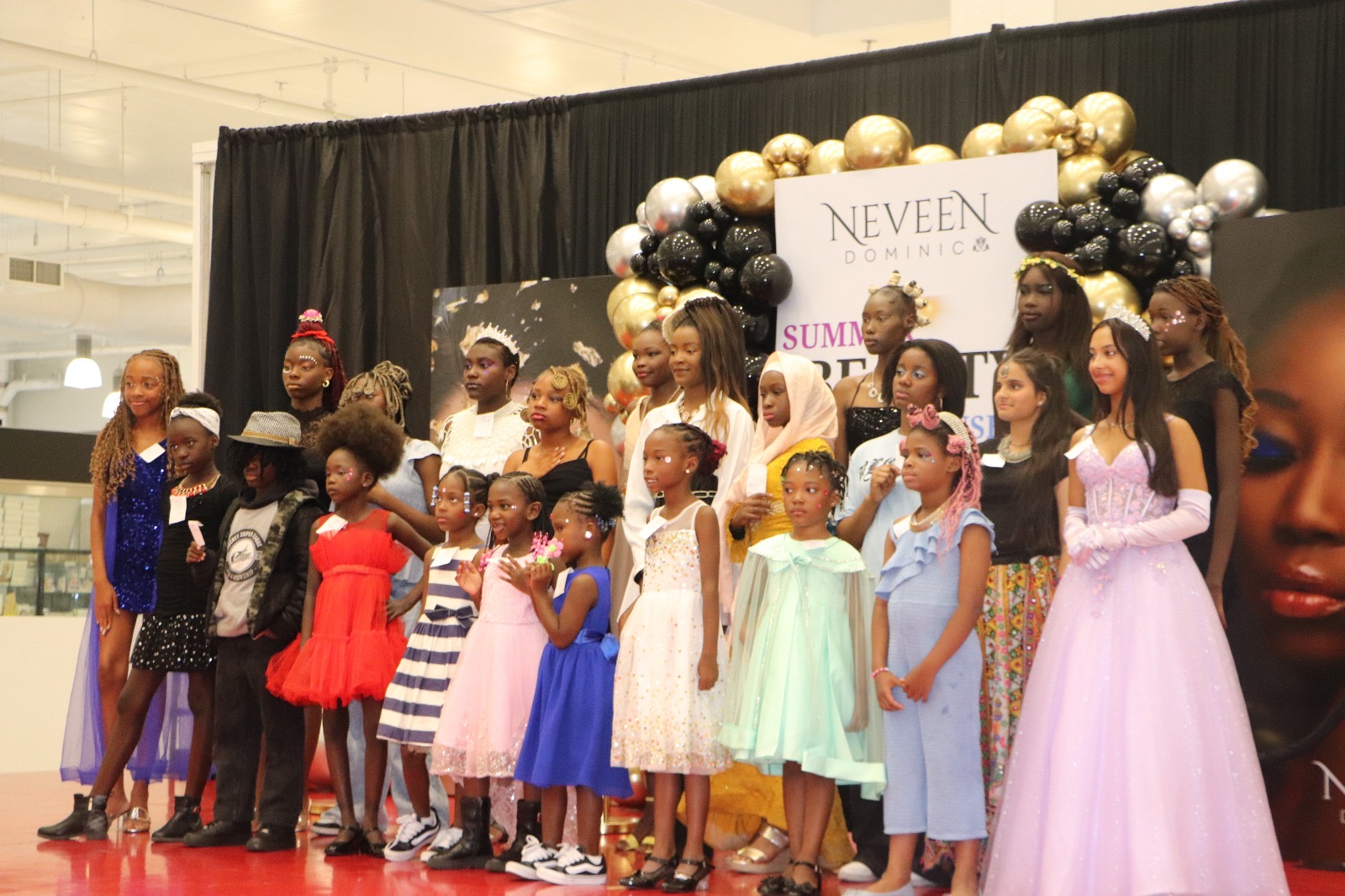Students line the stage in their showcase looks beneath the balloon arch