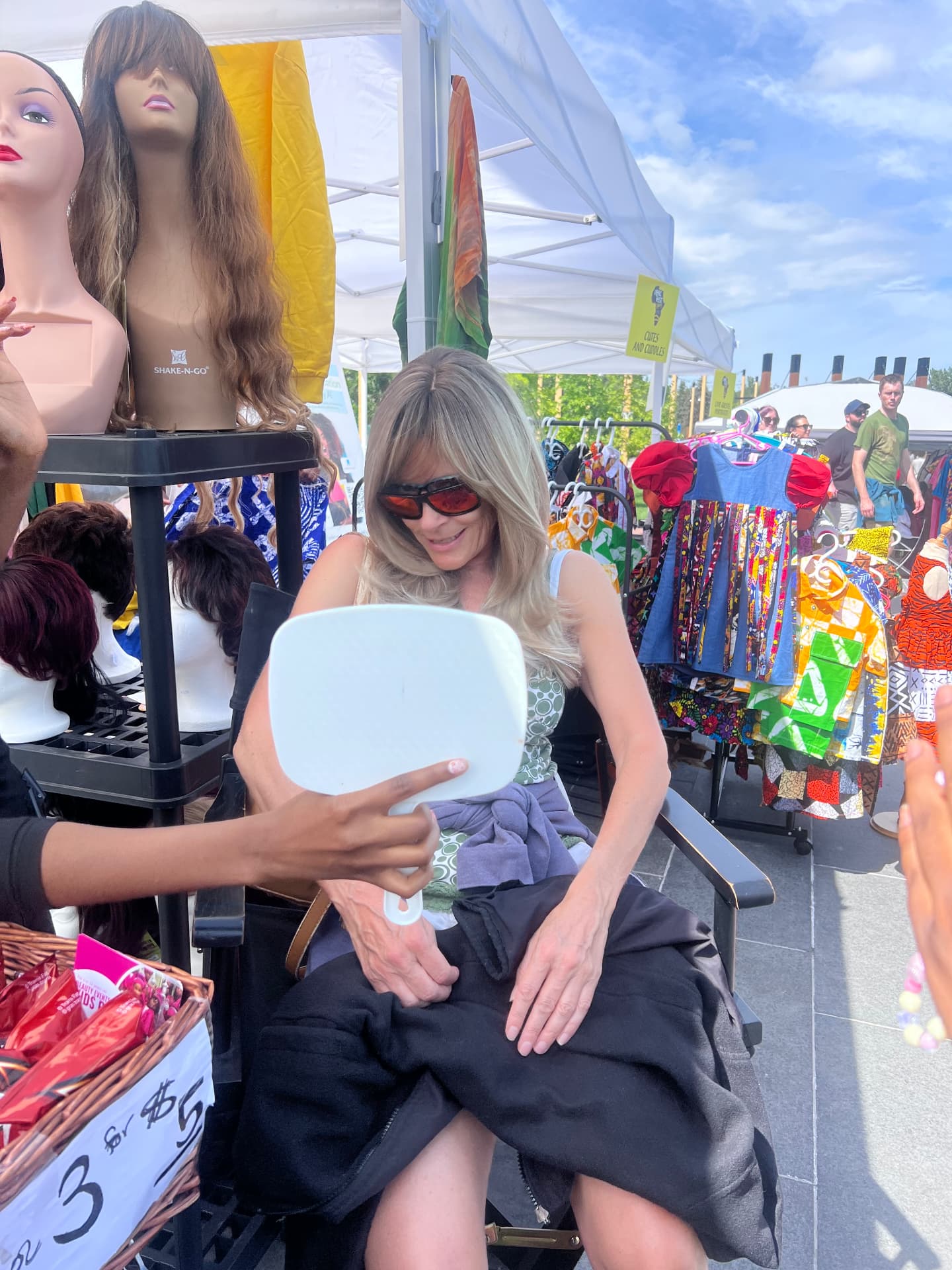 A student holds a mirror for a visitor to see her new look