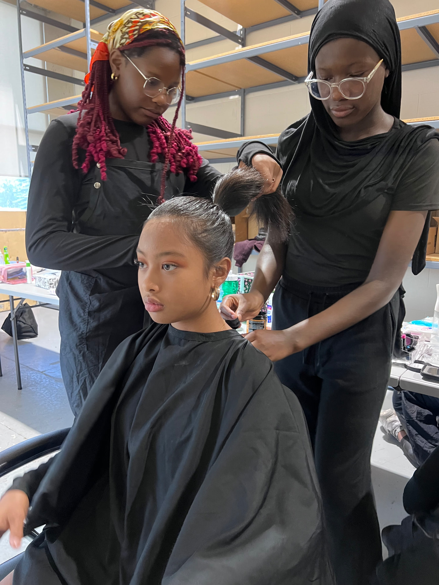 Two campers style a model's hair backstage before the runway