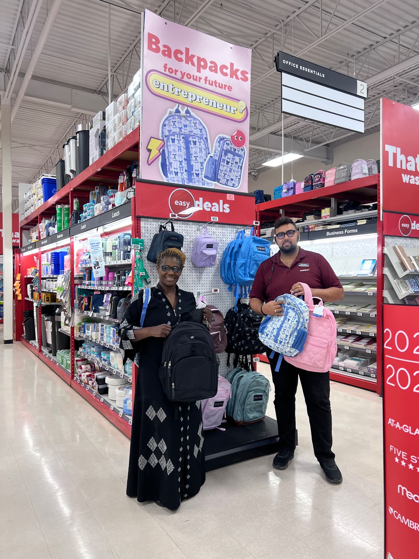 Two people choosing backpacks together in a store aisle